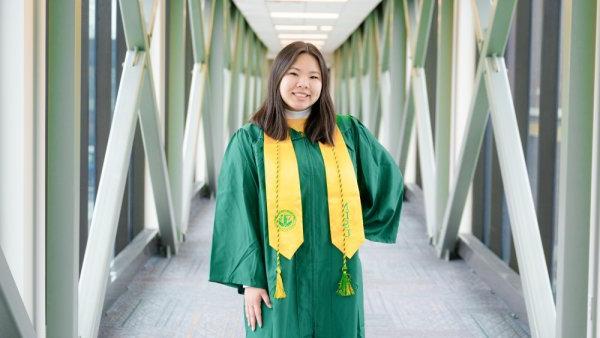 Nguyen smiling in commencement gown